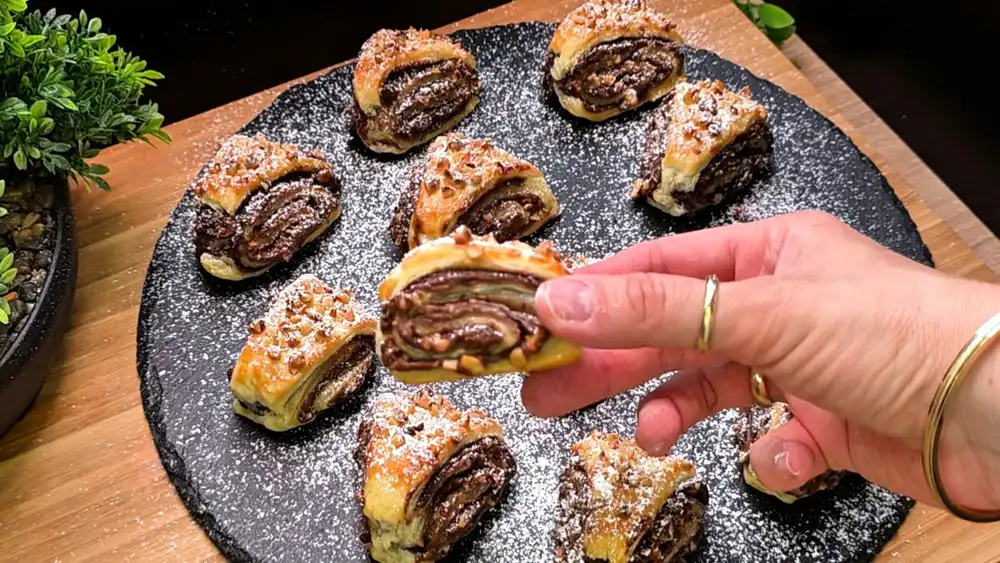 Detailansicht eines einzelnen gefüllten Nutella-Dreiecks mit Fokus auf die sichtbaren Schoko-Schichten und die knusprig gerösteten Nussstücke auf der Oberfläche.