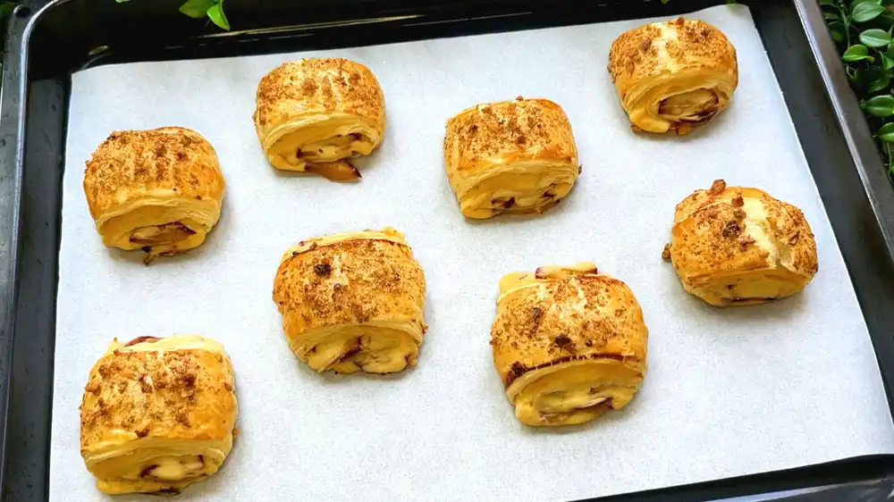 Goldbraun gebackene Blätterteig-Zwetschgen-Quark-Schnecken mit gehackten Walnüssen auf einem Servierbrett für den Schulstart.