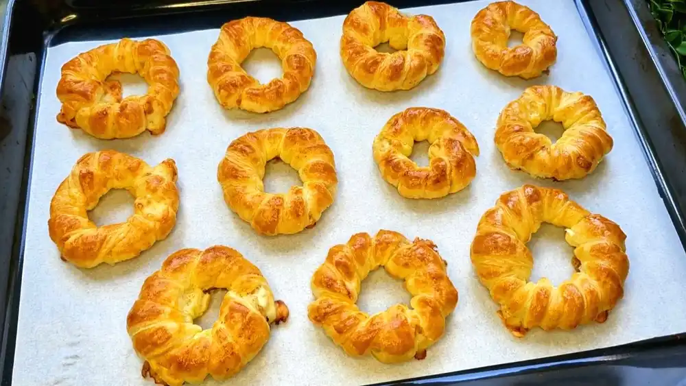Goldbraun gebackene Blätterteig-Zwiebelringe mit geschmolzenem Käsekern verpackt in einer Brotdose für den Schulstart.