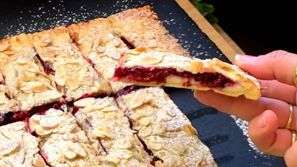 Detailansicht eines aufgeschnittenen Beeren-Riegels mit Fokus auf die rote Beerenfüllung, samtige Vanillecreme und den Blätterteigmantel.
