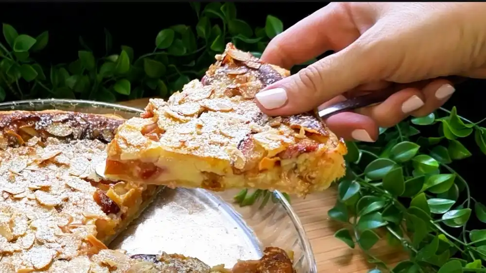 Detailansicht eines Tortenstücks von Käsekuchen mit Fokus auf die cremige Quarkfüllung, saftige Zwetschgenstücke und den Blätterteigrand.