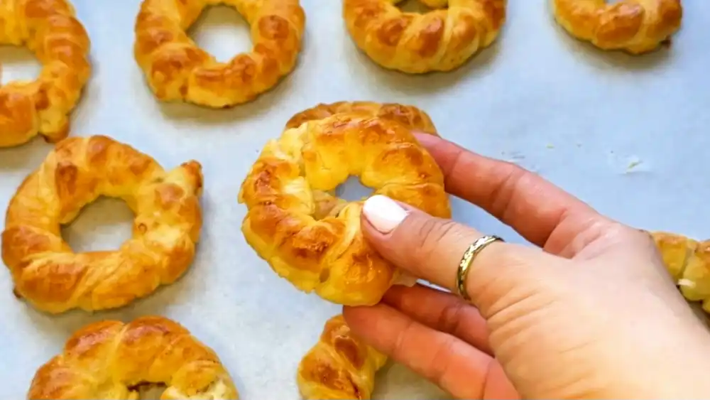 Detailansicht eines Blätterteig-Zwiebelrings mit Fokus auf den schmelzenden Käsekern, saftige Zwiebeln und die knusprige Teigumwicklung.
