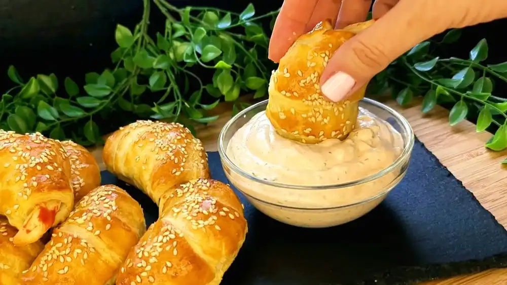 Detailansicht eines aufgeschnittenen Surimi-Croissants mit Fokus auf den knusprigen Teigmantel, die saftige Surimi-Füllung und die gerösteten Sesamkörner.