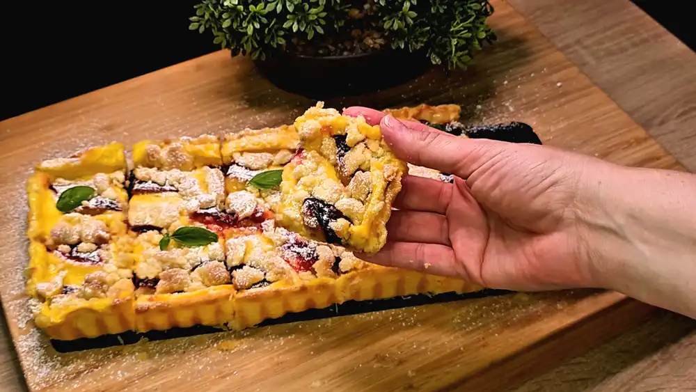 Detailansicht eines Kuchenstücks mit Fokus auf die dicke Vanillepudding-Schicht, saftige Zwetschgen und knusprige Butterstreusel.