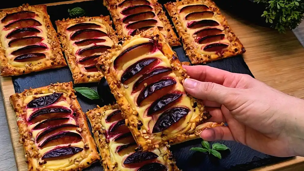 Detailansicht eines knusprigen Blätterteig-Mini-Kuchens mit cremigem Quark und gebackenen Zwetschgenscheiben.