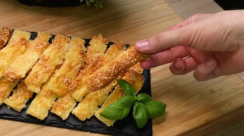 Detailansicht knuspriger Blätterteig-Käsestangen mit kross gebackenem Käse und Sesam-Topping.